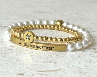 May include: Two-piece bracelet set. One bracelet features small gold beads and a gold bar with the inscription "I WILL LOVE YOU INTO ETERNITY." The other bracelet has white pearl beads. A gold charm with the letter "M" is also included.