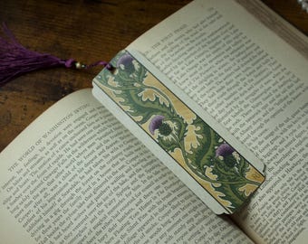 Marcador con ilustración de cardo victoriano, verde, morado y dorado, con borla de cuentas