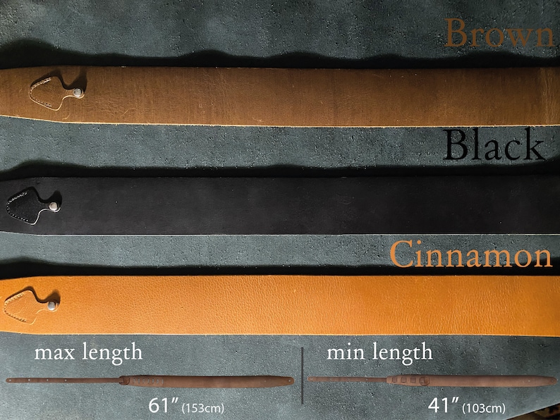 May include: Three leather guitar straps in brown, black, and cinnamon colors. The straps are shown laid out horizontally on a textured surface. The straps are adjustable and have a maximum length of 61 inches (153 cm) and a minimum length of 41 inches (103 cm).