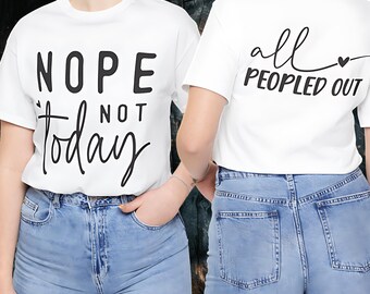 May include: White t-shirts with black text. One shirt says "Nope Not Today" and the other says "all Peopled Out" with a heart. The shirts are paired with light blue denim jeans. The image shows the front and back of the shirts.