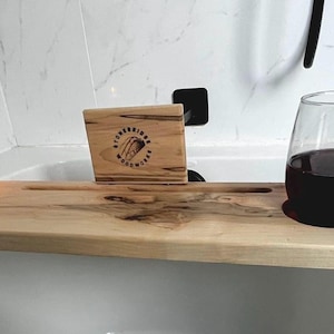 Peut inclure: Un plateau de bain en bois avec un verre de vin rouge, une bougie et une petite pancarte en bois avec le texte "The Everyday Escape".