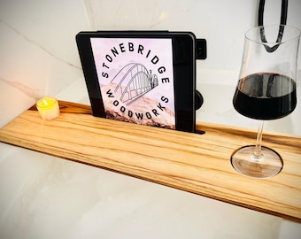 Peut inclure: Un plateau de bain en bois avec un support de téléphone intégré, un porte-verre à vin et un petit porte-bougie. Le plateau est en bois naturel avec une finition brun clair. Le support de téléphone est en métal noir et peut contenir une tablette ou un téléphone. Le porte-verre à vin est en verre transparent et peut contenir un verre à vin de taille standard. Le porte-bougie est en verre transparent et peut contenir une petite bougie chauffe-plat.