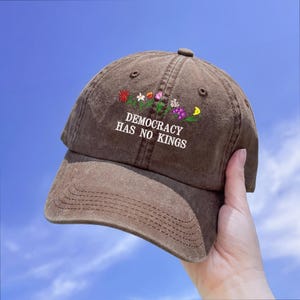 Puede incluir: Una taza de cerámica blanca con un asa negra y el texto "But First, Coffee" en negro, con una fuente de estilo manuscrito. La taza está sobre una superficie blanca.