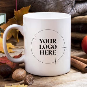 May include: White ceramic mug with a black circle and the text "YOUR LOGO HERE" inside. The circle is decorated with small black stars.