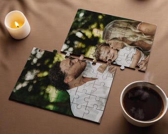 May include: A jigsaw puzzle with a photo of a family of three. The puzzle is partially assembled, with the top half showing a woman kissing a child on the cheek. The bottom half shows a man kissing the child on the forehead. The puzzle pieces are white with black lines.