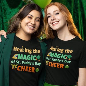 May include: Two people wearing black t-shirts with green shamrock and rainbow graphics. The text on the shirts reads "Hearing the Magic of St. Paddy's Day Cheer".
