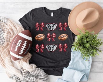 May include: A dark gray t-shirt with a red and white design featuring an elephant, footballs, and bows.