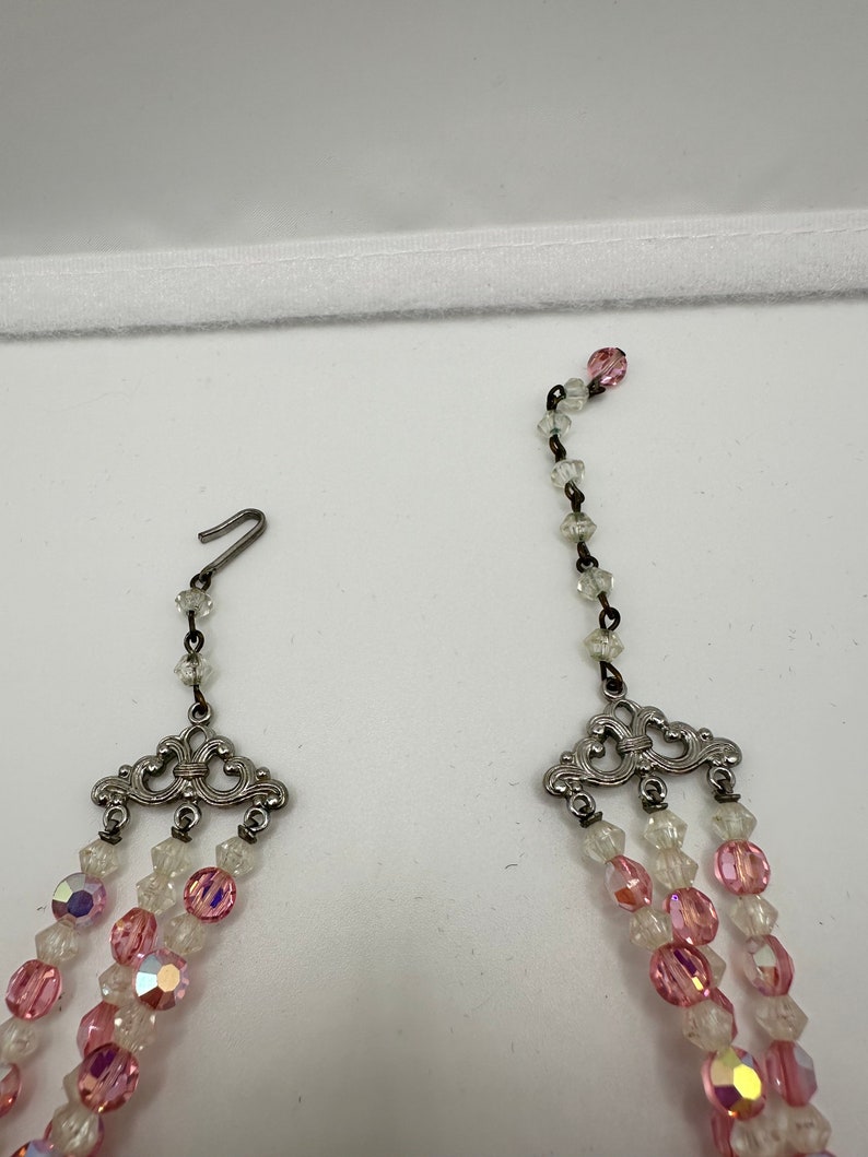 May include: A multi-strand necklace with pink and clear glass beads. The necklace has a silver clasp and decorative silver accents.
