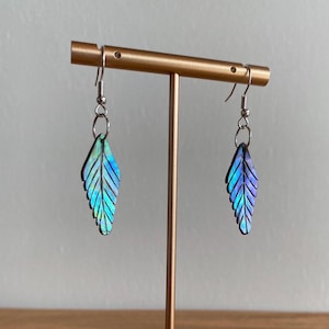 May include: A pair of iridescent blue and green leaf-shaped earrings with silver hooks.