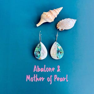 May include: A pair of teardrop-shaped earrings featuring a split design of iridescent abalone shell and white mother of pearl, suspended from silver-toned wire hooks. The text Abalone & Mother of Pearl is printed below the earrings.