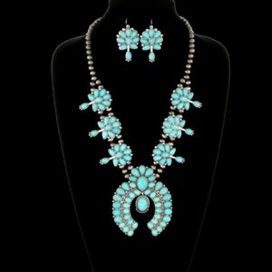 May include: A turquoise and silver Native American style necklace and earrings set. The necklace features a large turquoise horseshoe pendant with smaller turquoise flowers and silver beads. The earrings are also turquoise and silver with a flower design.