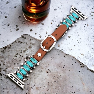 Puede incluir: Una correa de Apple Watch de cuero marrón con un diseño de piedra turquesa y hebilla plateada.