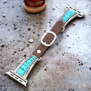 Puede incluir: Una correa de reloj de cuero marrón con una hebilla plateada e incrustaciones de turquesa. La correa está diseñada para un Apple Watch.