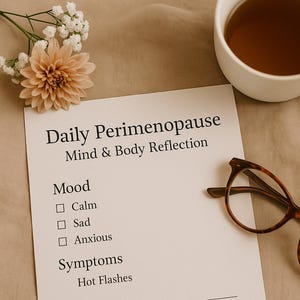 May include: A still-life image featuring a white mug of tea, a sheet of paper with the text "Daily Perimenopause Mind & Body Reflection", and a pair of tortoiseshell glasses. A peach-colored flower and white flowers are also present.