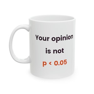 Könnte beinhalten: Weiße Keramiktasse mit dem Text "Your opinion is not p < 0.05" in Schwarz und Orange gedruckt.