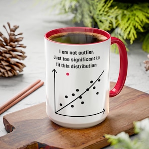 May include: White ceramic mug with a red interior and handle, filled with coffee. The mug features a graph with the text "I am not outlier. Just too significant to fit this distribution."