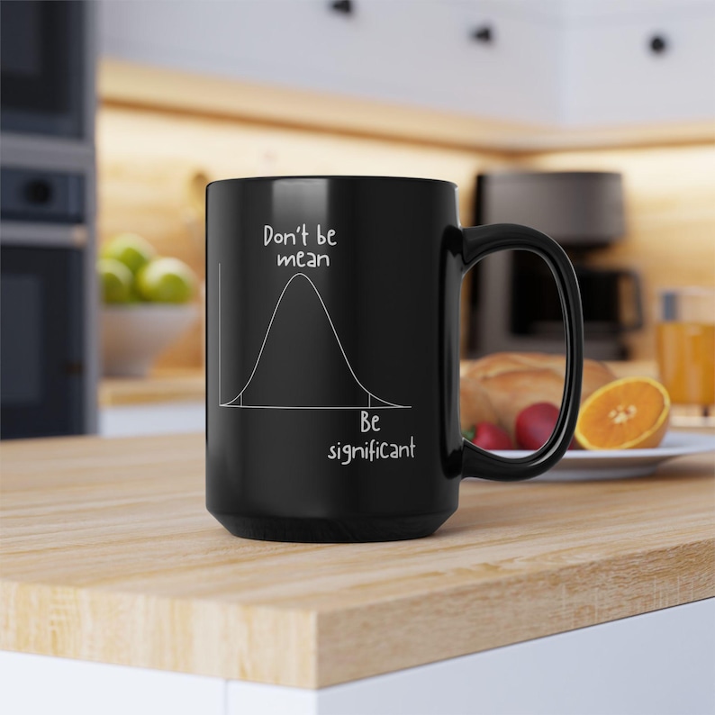 May include: A black ceramic mug featuring a white line drawing of a bell curve distribution graph. The text "Don't be mean" is printed above the curve, and the text "Be significant" is printed below the curve on the right side.
