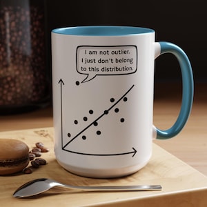 May include: A white ceramic mug with a light blue interior and handle. The exterior features a black line graph with data points and a speech bubble containing the text: I am not outlier. I just don't belong to this distribution.