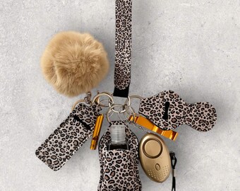May include: A leopard print keychain with a fluffy pom-pom, a hand sanitizer holder, a bottle opener, and a personal alarm.