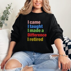 Peut inclure: Un sweat-shirt noir avec le texte "Je suis venu, j'ai enseigné, j'ai fait une différence, je suis parti à la retraite" en couleurs arc-en-ciel.