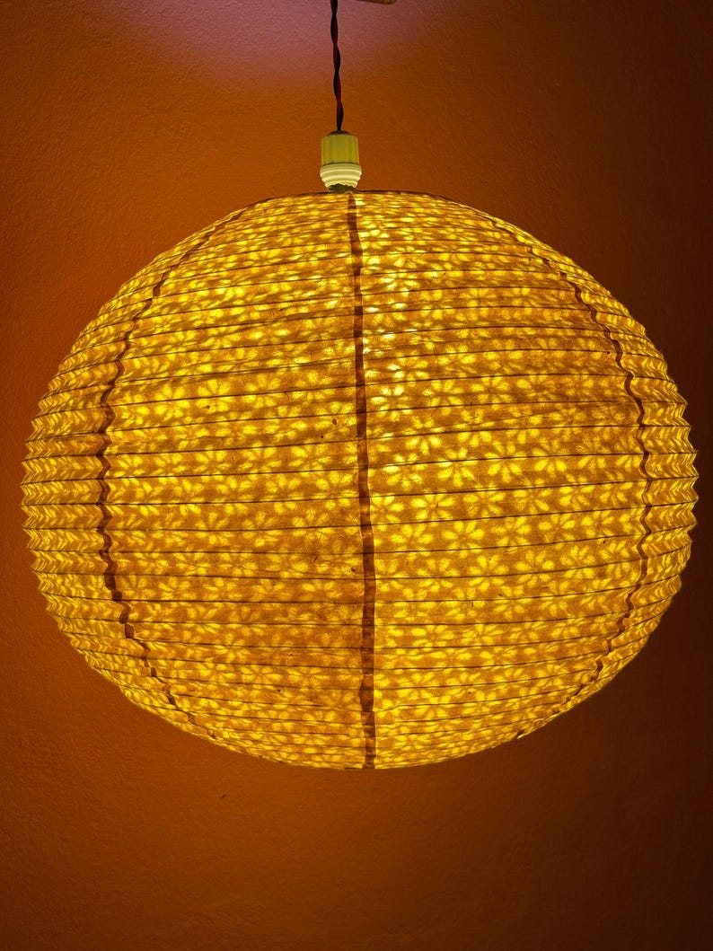 Golden yellow flower paper lampshade hanging in a boho-style room