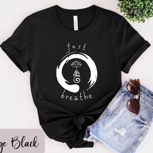 May include: Black t-shirt with white text that reads "just breathe" and a white lotus flower inside a circle.