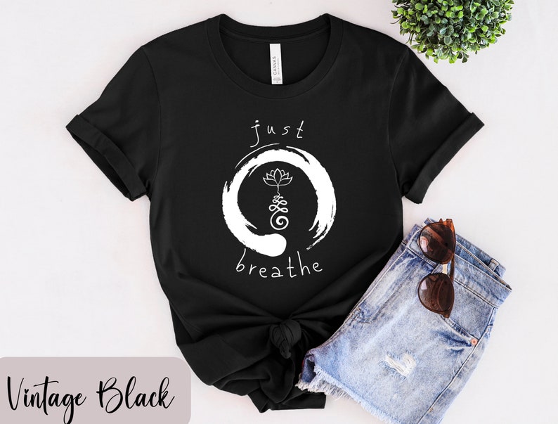 May include: Black t-shirt with white text that reads "just breathe" and a white lotus flower inside a circle.