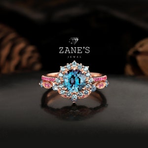 May include: A rose gold engagement ring set with a blue gemstone surrounded by smaller blue and pink gemstones. The ring is set on a black background.