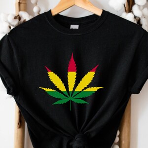 May include: Black t-shirt featuring a red, yellow and green marijuana leaf design.