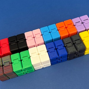 May include: A selection of colourful fidget toys in shades like red, black, pink, blue, orange, purple, and yellow. Each toy is made of linked blocks, forming a flexible, bendable structure. The background is a solid blue.