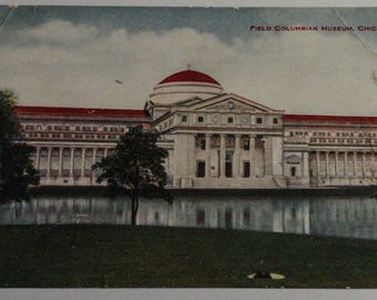 May include: A vintage postcard featuring a black and white photograph of the Field Columbian Museum in Chicago. The building is a large, white structure with a red roof and a dome. The building is surrounded by trees and grass.