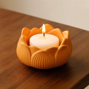 May include: A burning white candle in an orange ceramic lotus flower-shaped holder. The candle holder has a textured surface and is on a wooden surface. The flame is bright, creating a warm and inviting atmosphere. The candle holder is approximately 10 cm in diameter.