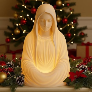 Può includere: Una statua religiosa color crema di una donna con un velo drappeggiato, le mani giunte in grembo e gli occhi chiusi. La statua è illuminata dall'interno, creando un bagliore soffuso. Lo sfondo include un albero di Natale con luci e ornamenti.