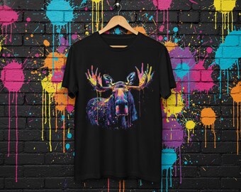 以下が含まれることがあります： カラフルなヘラジカのデザインが施された黒いTシャツ。ヘラジカは大きな角を持ち、鮮やかなペイントスプラッターで覆われています。デザインは黒い背景に設定されています。