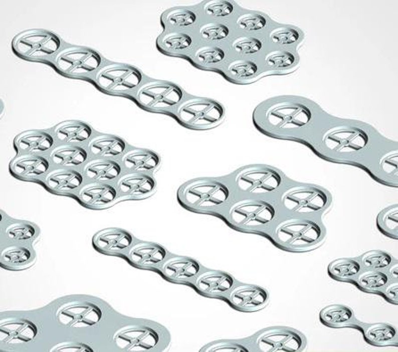 May include: A set of silver metal stencils with circular cutouts in various shapes and sizes. The stencils are designed for crafting and creating patterns.