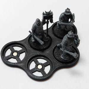 May include: A black plastic miniature figure display stand with five circular slots. Three miniature figures are displayed on the stand. The figures are gray and are holding weapons.