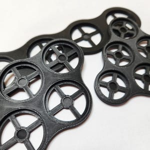 May include: A black plastic organizer with multiple circular compartments, each with a star-shaped cutout. The organizer is designed to hold small items, such as coins or buttons.