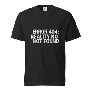 Może przedstawiać: Czarny t-shirt z krótkim rękawem z białym nadrukiem na klatce piersiowej o treści ERROR 404: REALITY NOT NOT FOUND. Napis ma postarzany, glitchowy wygląd z poziomymi liniami przechodzącymi przez poszczególne znaki.