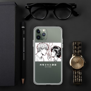 May include: A gray smartphone case featuring a black and white manga-style illustration of two people facing each other, with red smoke lines and Japanese text that reads 共有された静寂 and 都市の物語, positioned between black glasses, a pencil, and a watch.