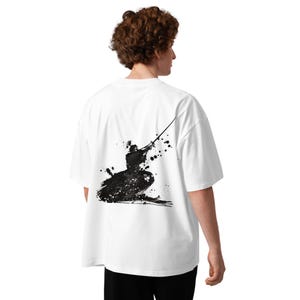 Può includere: Una t-shirt bianca a maniche corte con una grafica nera in stile inchiostro sul retro. Il design raffigura la silhouette di un samurai in posizione inginocchiata, che tiene una katana rivolta verso l'alto, circondato da schizzi di vernice nera.