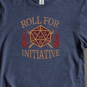 May include: A blue t-shirt with the text "Roll for Initiative" and a graphic of a 20-sided die with crossed swords.