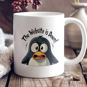 May include: White ceramic coffee mug with a black and white cartoon penguin illustration. The text "The Website is Down!" is printed on the mug.