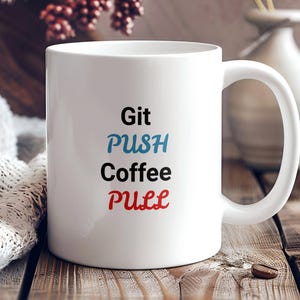 May include: White ceramic coffee mug with the text "Git PUSH Coffee PULL" in blue and red lettering.