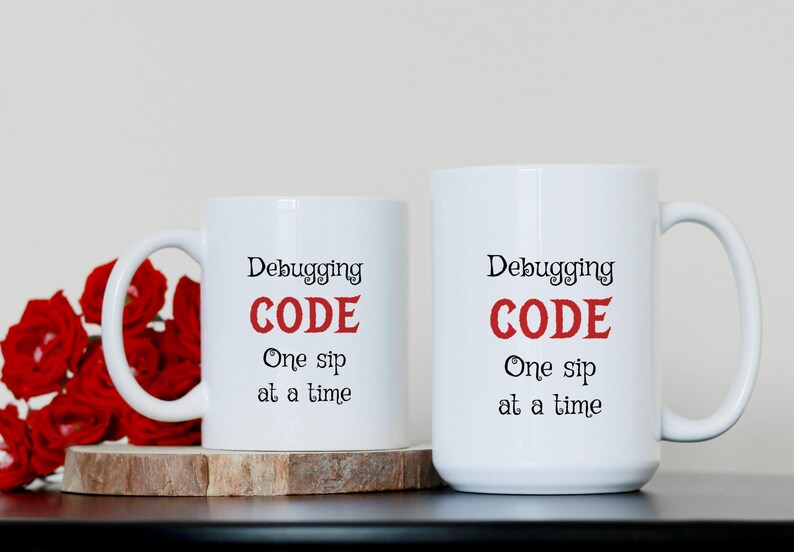 Może przedstawiać: Dwa białe kubki do kawy z czarnym tekstem i czerwonym tekstem, kt&oacute;ry brzmi "Debugging CODE One sip at a time".