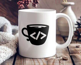 May include: White ceramic coffee mug with a black and white illustration of a coffee cup with the code "</>" inside.