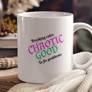May include: White ceramic mug with the text "Breaking rules Chaotic Good To fix problems" in pink, green, and black lettering.