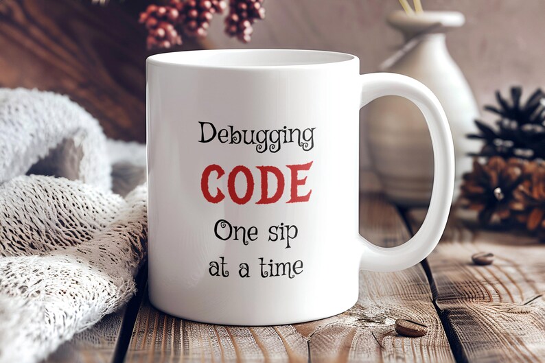 Może przedstawiać: Biały ceramiczny kubek do kawy z napisem "Debugging CODE One sip at a time" w czarnym i czerwonym kolorze.