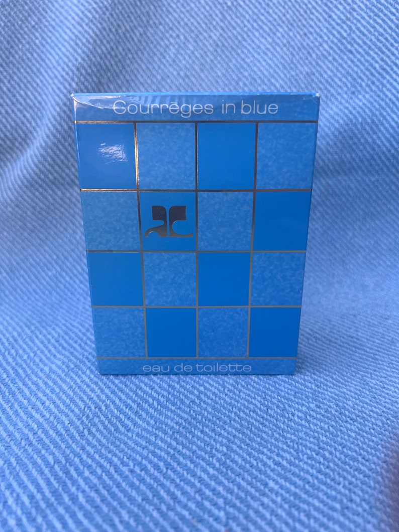 May include: A blue and silver box with the text "Courreges in blue" and "eau de toilette" on it. The box has a grid pattern and the letter "C" in a stylized font.