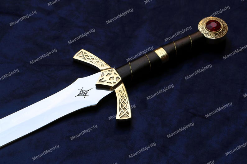 May include: A gold and silver sword with a black leather handle and a red jewel on the pommel. The sword has a Celtic knot design on the hilt and a silver blade.