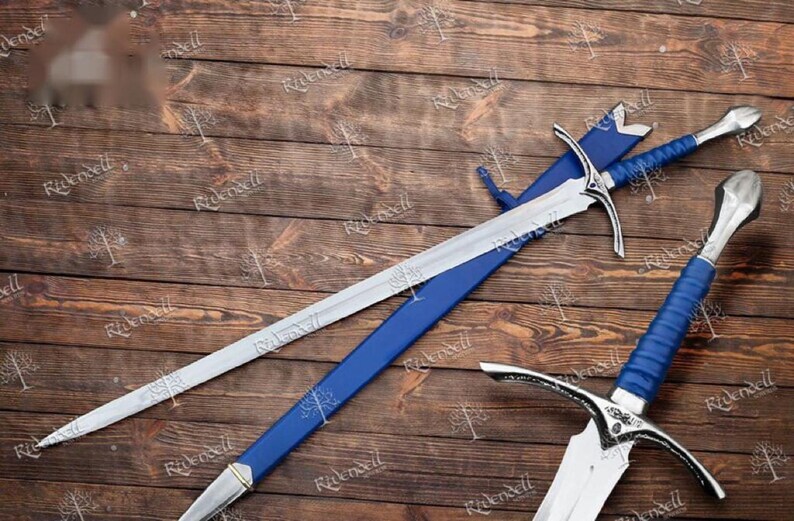 May include: Two silver swords with blue handles and scabbards. The swords are lying on a wooden surface.